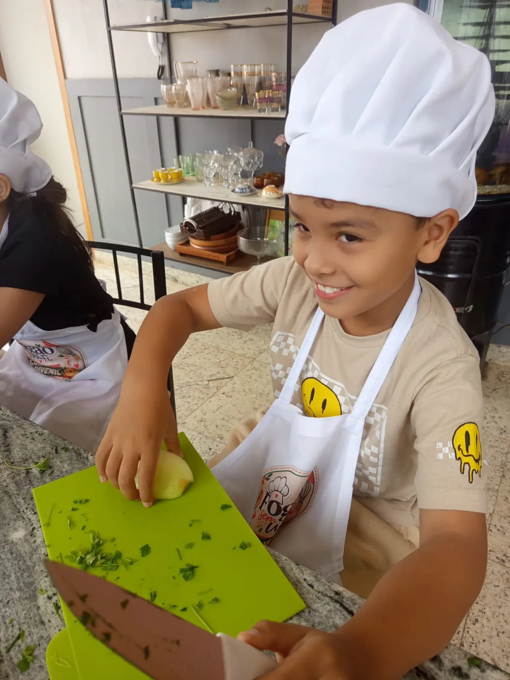 Aluno com touca e avental preparando ingredientes na bancada